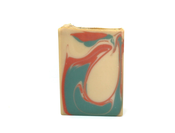 Tan Colored soap with copper and green swirls on white background.