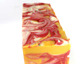 Bars of Swirled yellow soap with red and white accents on white background.
