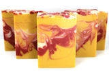 Staggered Swirled yellow soap with red and white accents on white background.