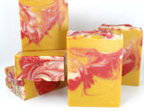 Stacked Swirled yellow soap with red and white accents on white background.