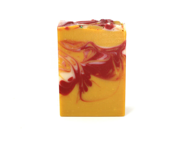 Swirled yellow soap with red and white accents on white background.